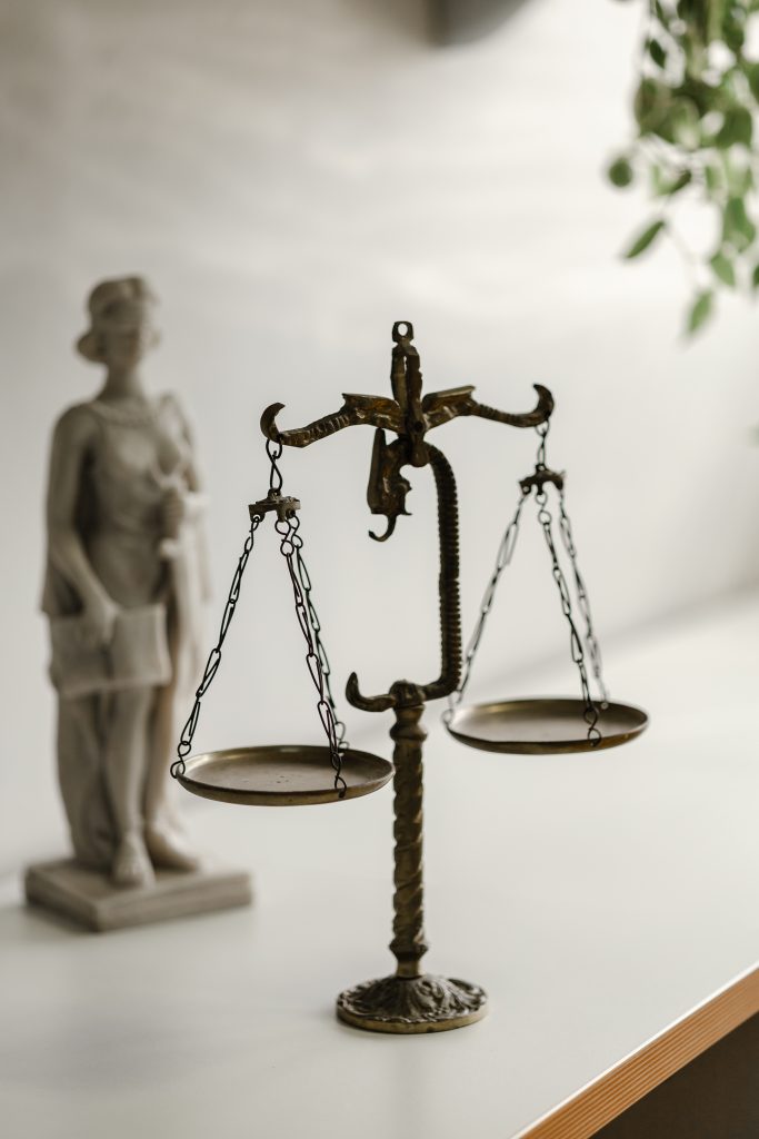 Balança e deusa Têmis ao fundo sobre uma bancada